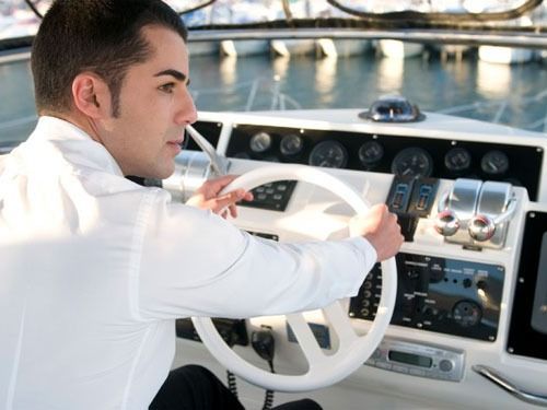 Un hombre con camisa blanca conduce un barco.