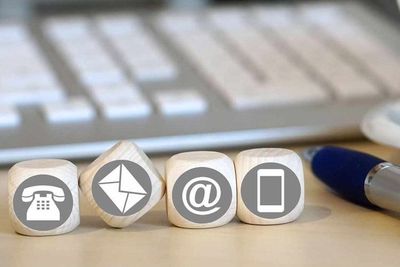 Una fila de dados con íconos de contacto sobre ellos se encuentran sobre una mesa frente a un teclado.