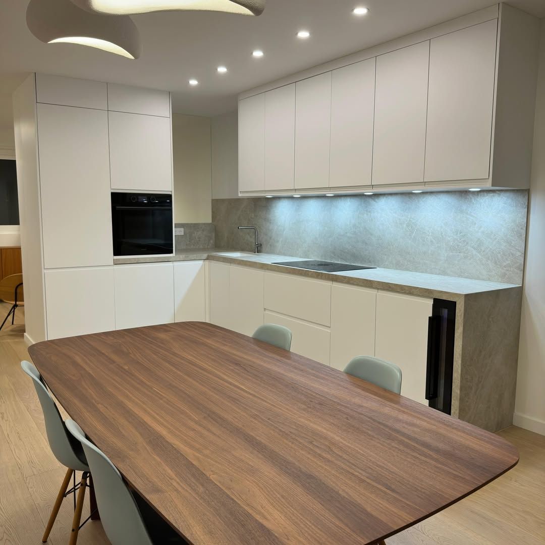 Cuisine blanche moderne avec table et chaises en bois.