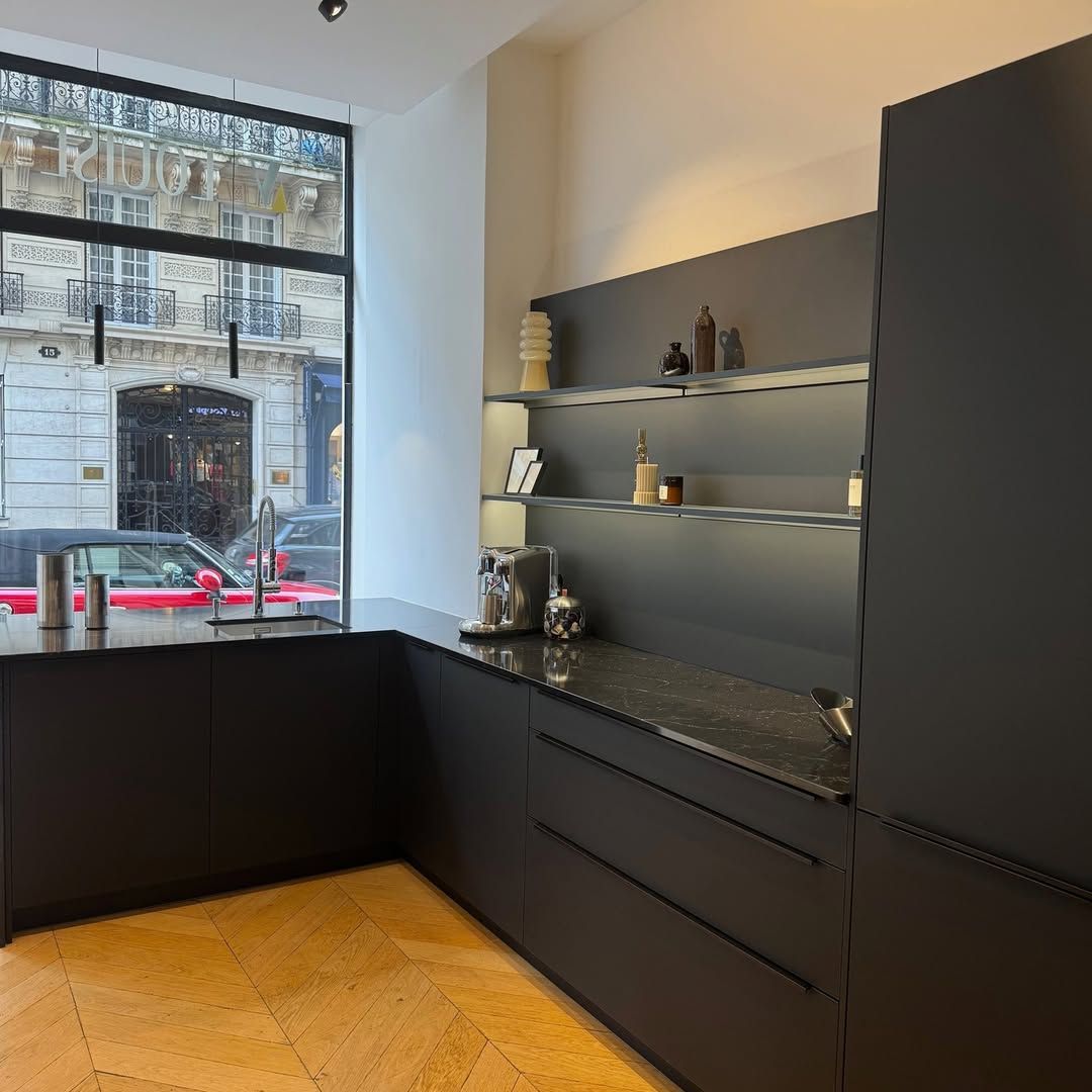 Cuisine moderne gris foncé avec une grande fenêtre et un sol en bois.