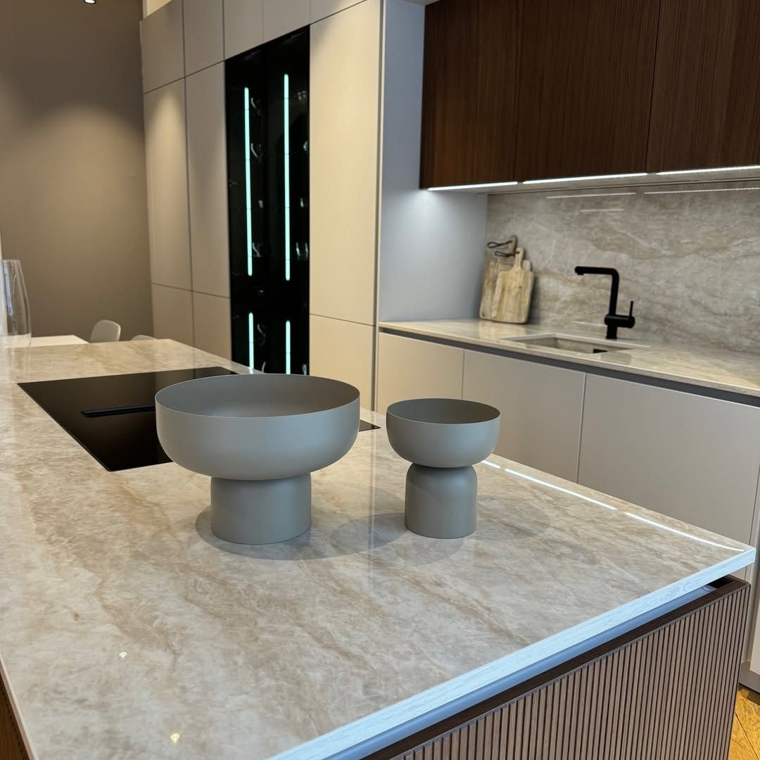 Cuisine avec plan de travail en marbre clair, deux vasques grises et appareils électroménagers foncés.