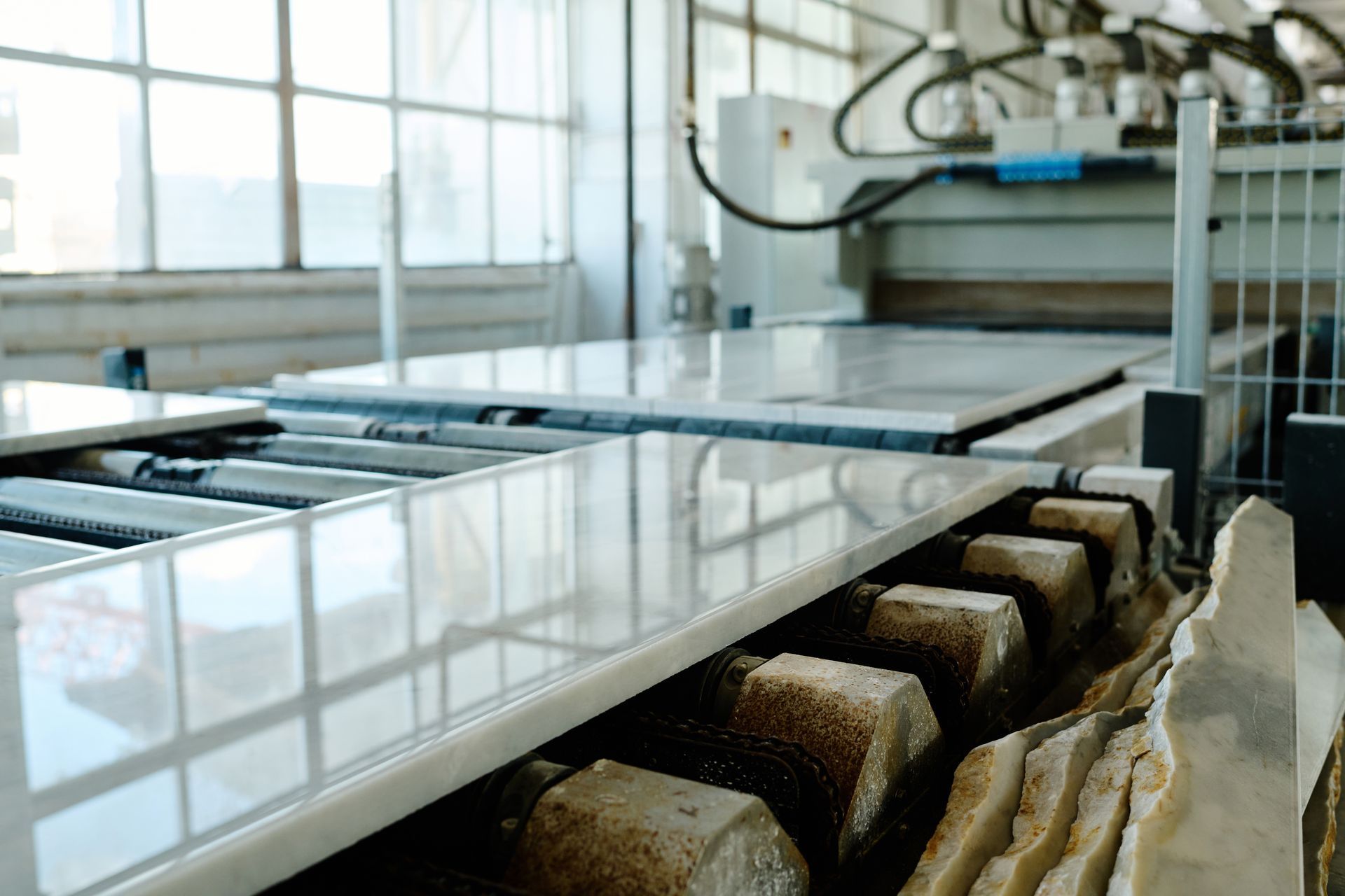 Atelier de production avec machines automatisées traitant des dalles de pierre polie.