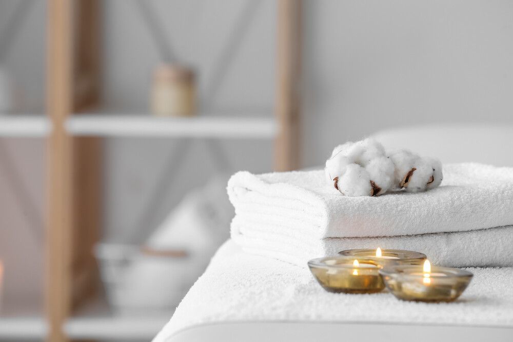 Una pila de toallas y velas sobre una mesa en un baño.