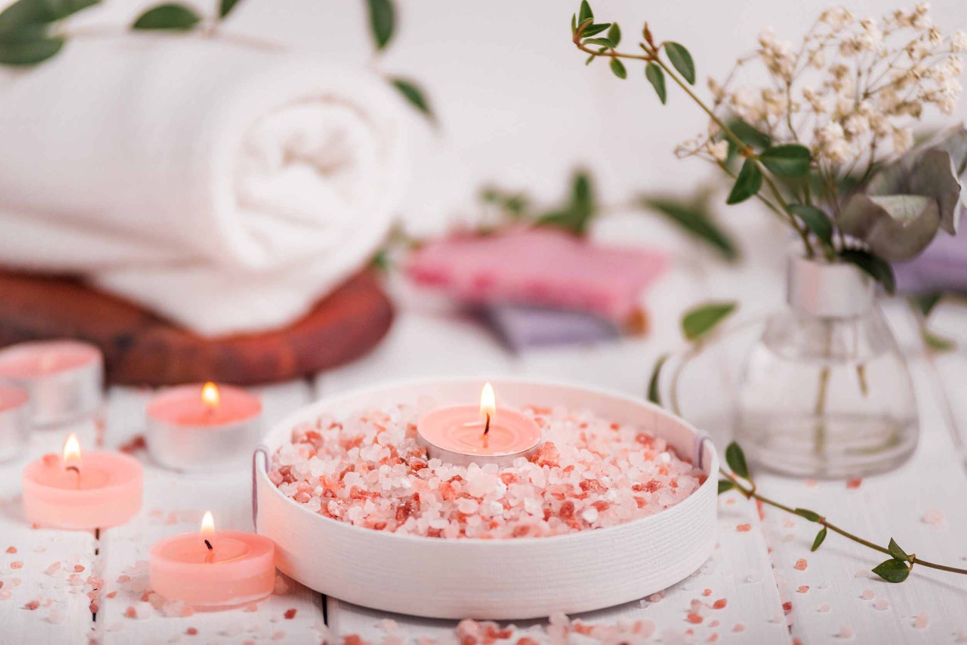 Un recipiente con sal rosa y velas sobre una mesa.
