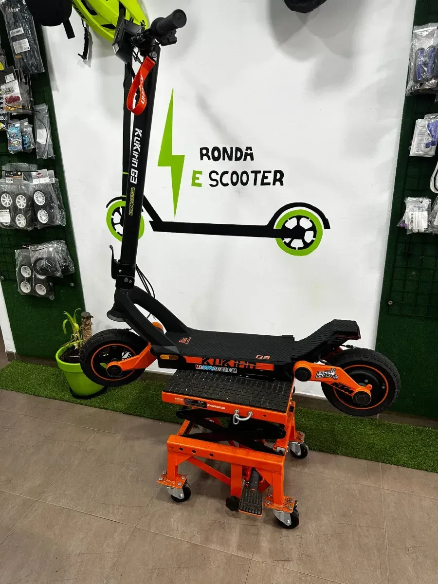 Patinete eléctrico negro y naranja en un elevador naranja, contra una pared con el cartel 