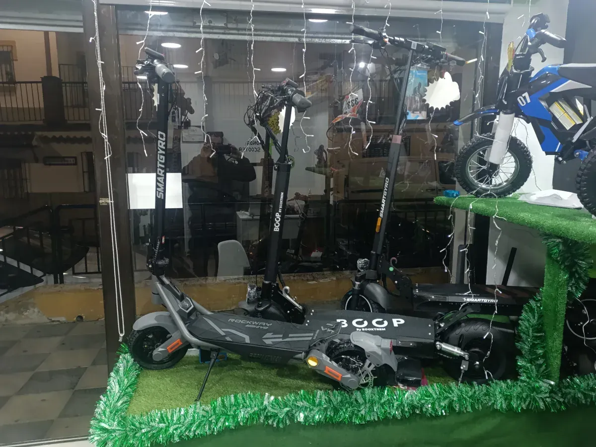 Patinetes eléctricos expuestos en un escaparate, iluminados con luces de colores.