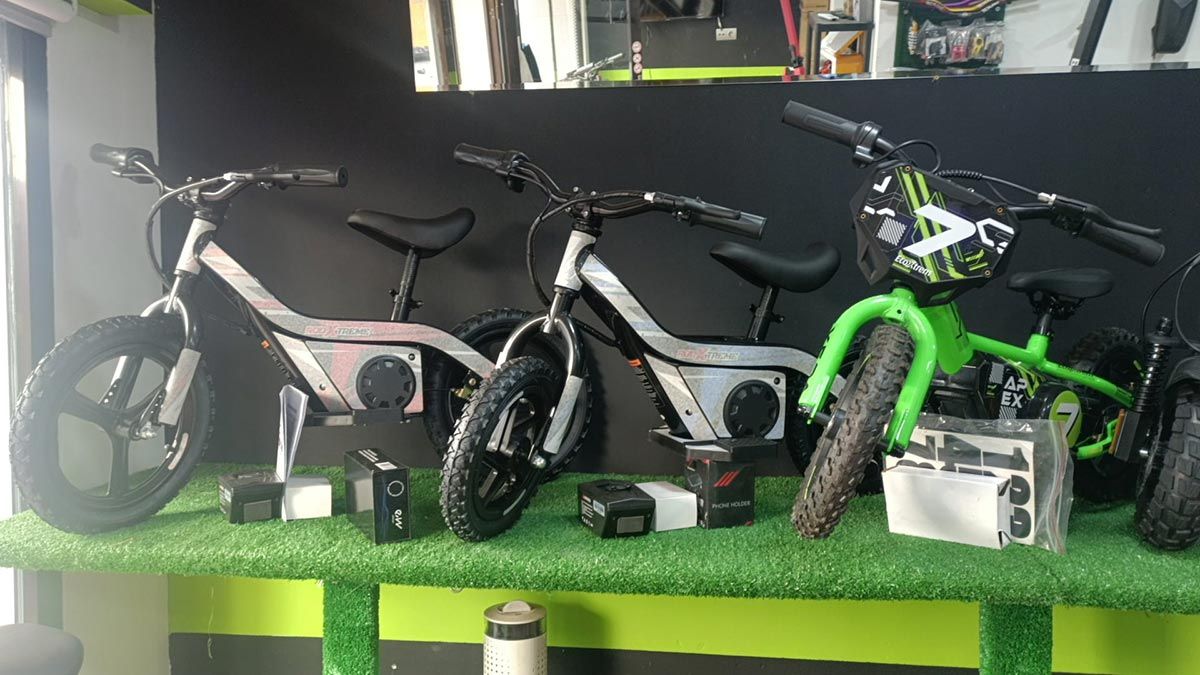 Tres bicicletas expuestas en un estante, incluyendo una bicicleta de color verde brillante junto a bicicletas blancas y negras.