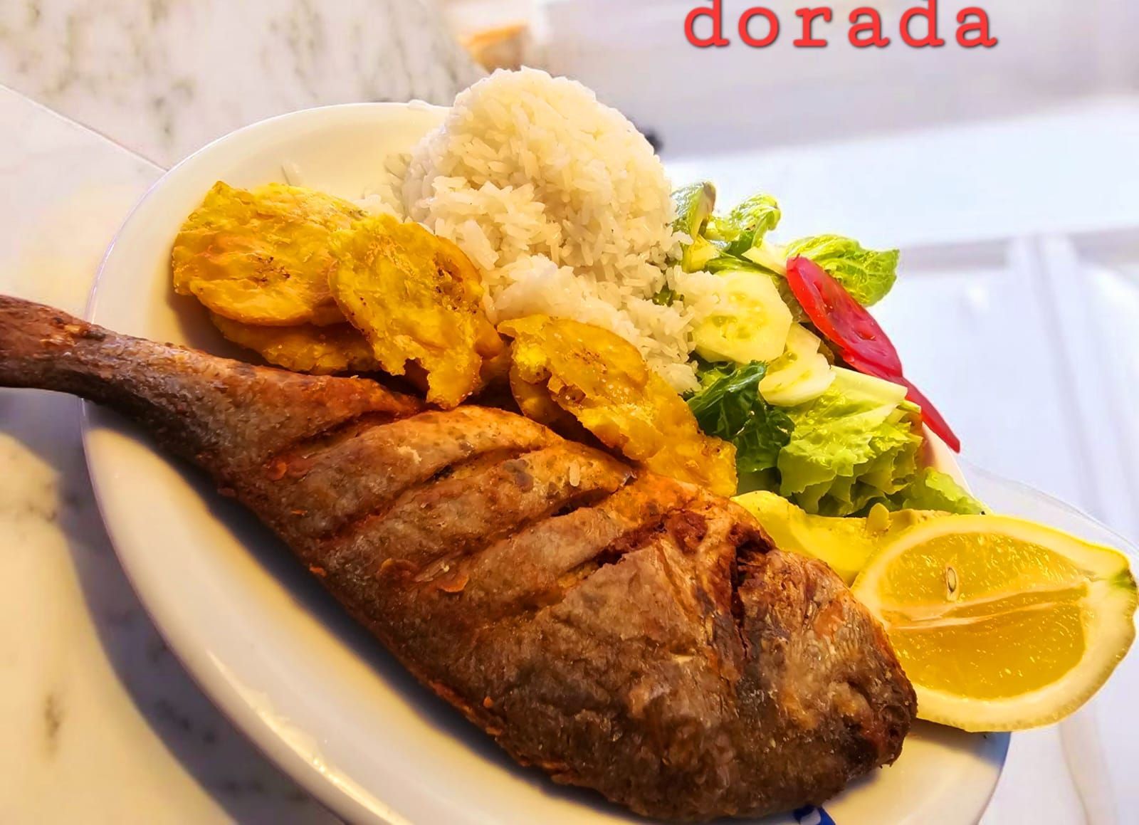 Pescado dorado frito con arroz, plátanos, ensalada y limón.