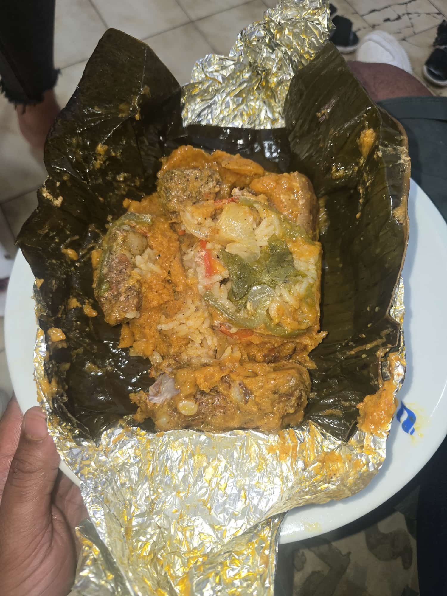 Tamal en un plato, envuelto en hoja de plátano y papel aluminio. Se ve el relleno.
