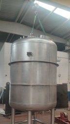 Tanque industrial de acero inoxidable siendo levantado por una grúa dentro de una fábrica.