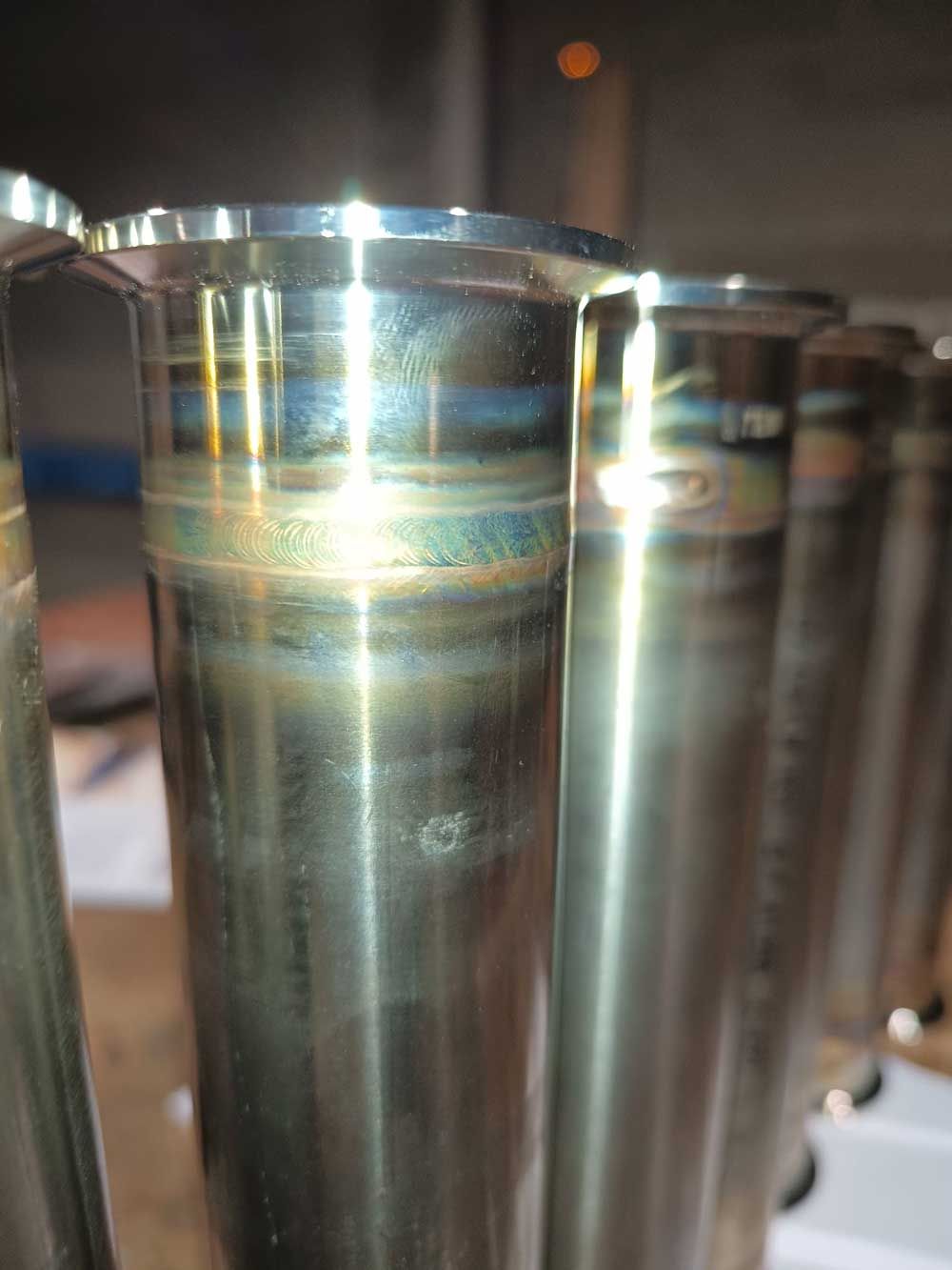 Primer plano de varios tubos de metal brillantes con decoloración por calor.