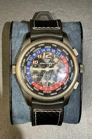 Un reloj está sobre un cojín azul sobre una mesa.