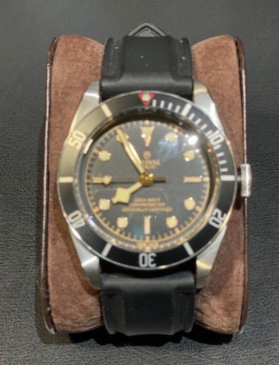 Un reloj Tudor está sobre una pulsera marrón.