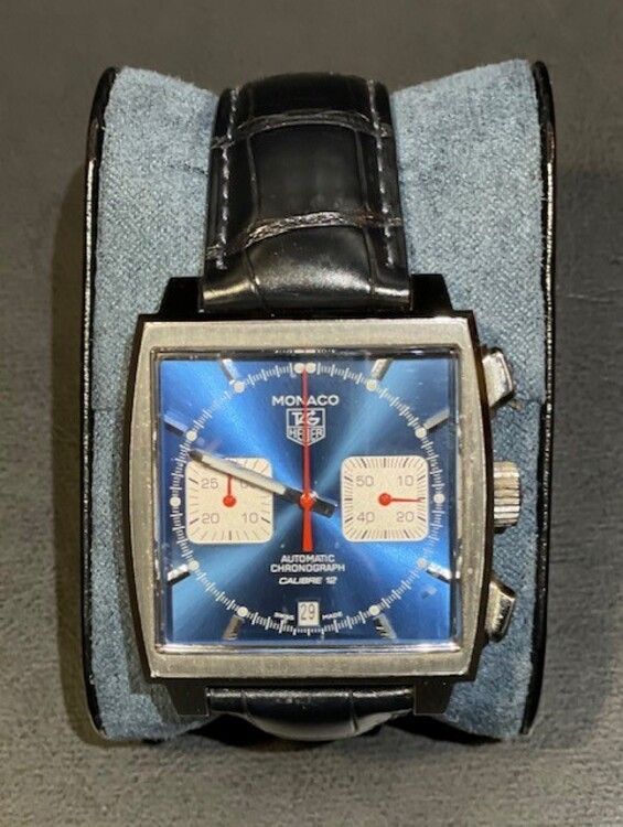Un reloj Monaco con esfera azul y correa negra.