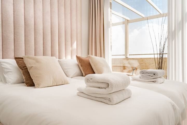 A bed with a stack of towels on top of it in a kosher airbnb.