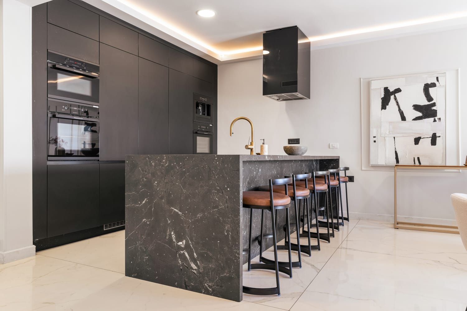 An airbnb kosher kitchen with black cabinets and a large island with stools.