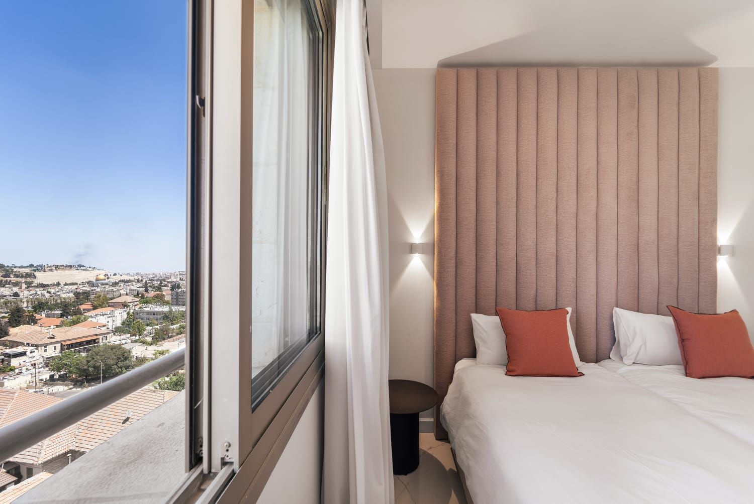 A Kosher Airbnb room with a bed and a window with a view of the old city of Jerusalem