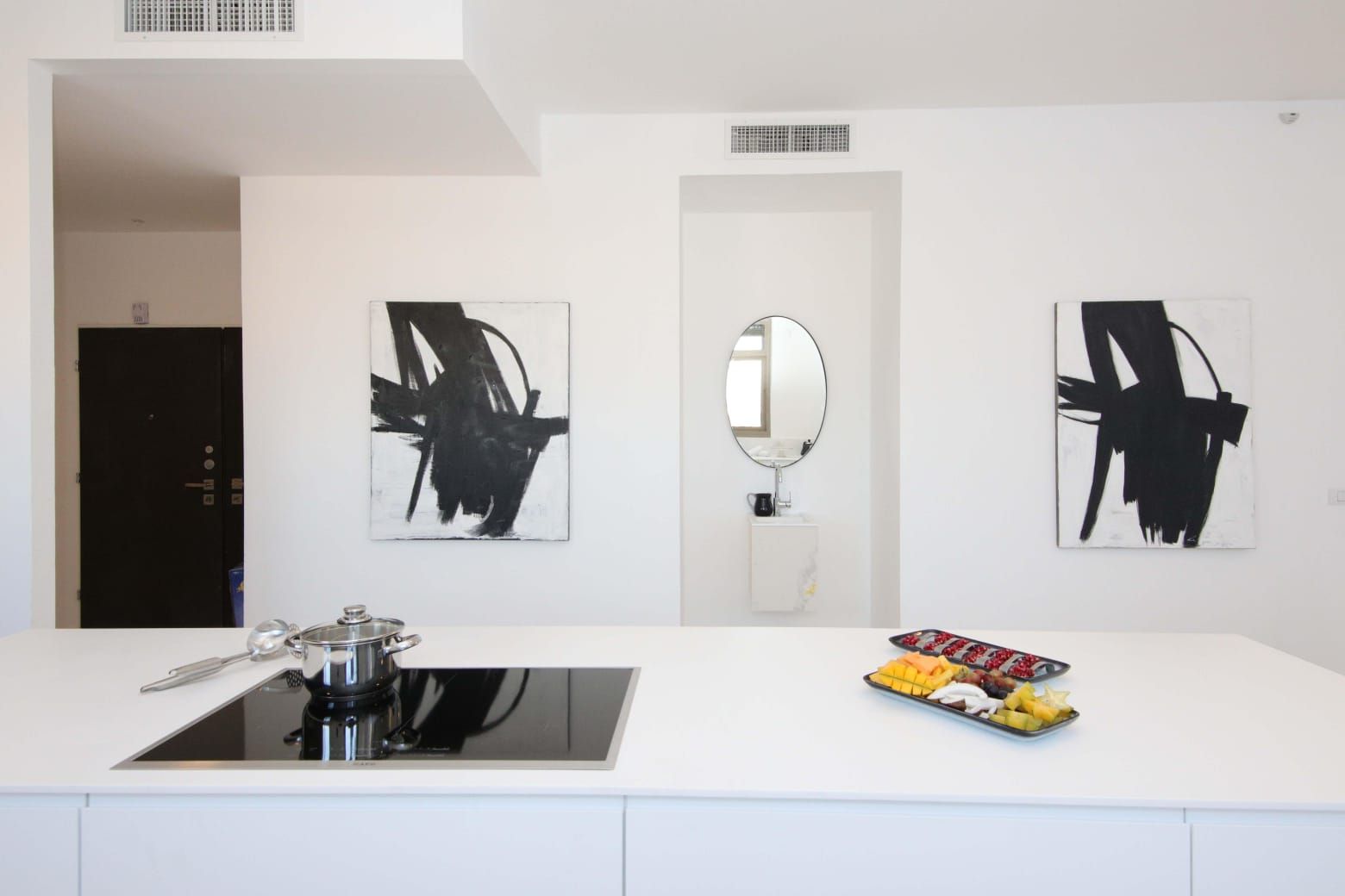 An airbnb kosher kitchen with black and white paintings on the wall