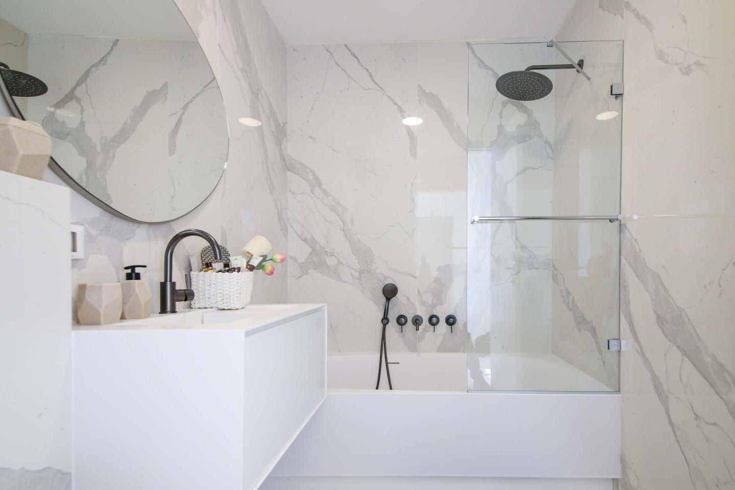 A bathroom with a sink , tub , shower and mirror.