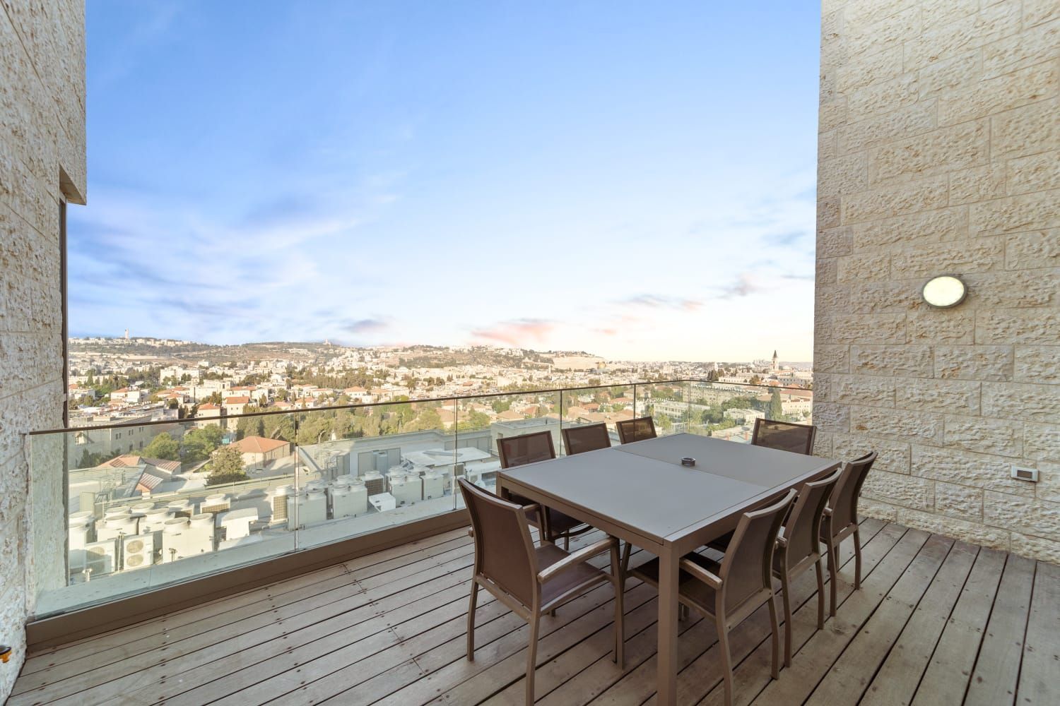 There is a table and chairs on the balcony with a view of Jerusalem. Penthouse terrace