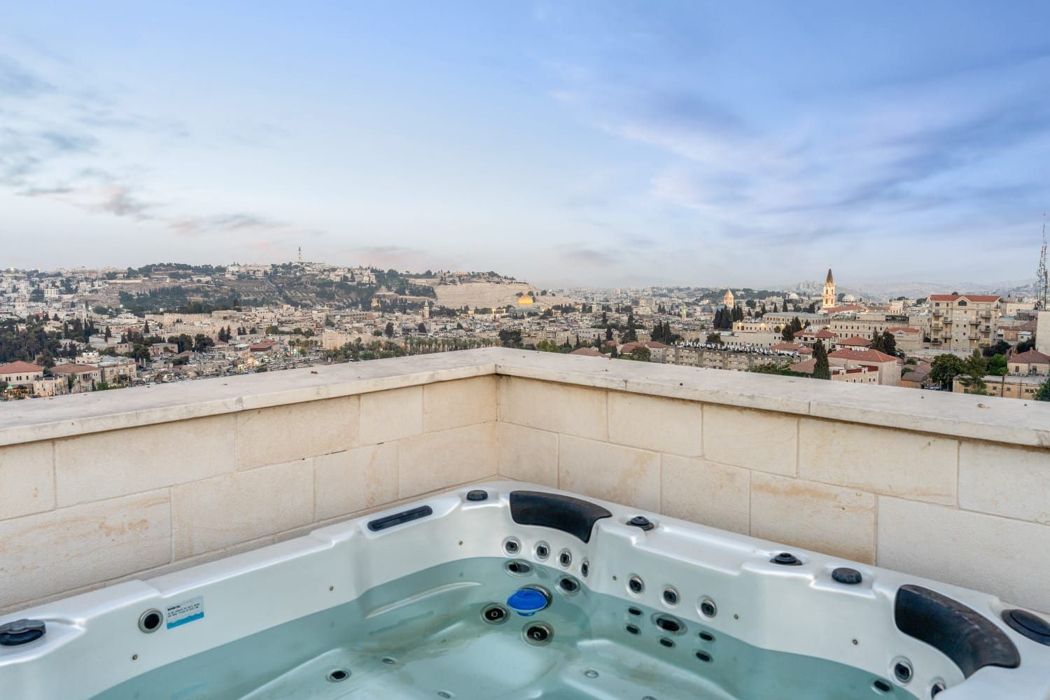 A hot tub on a rooftop with a view of jerusalem old city.