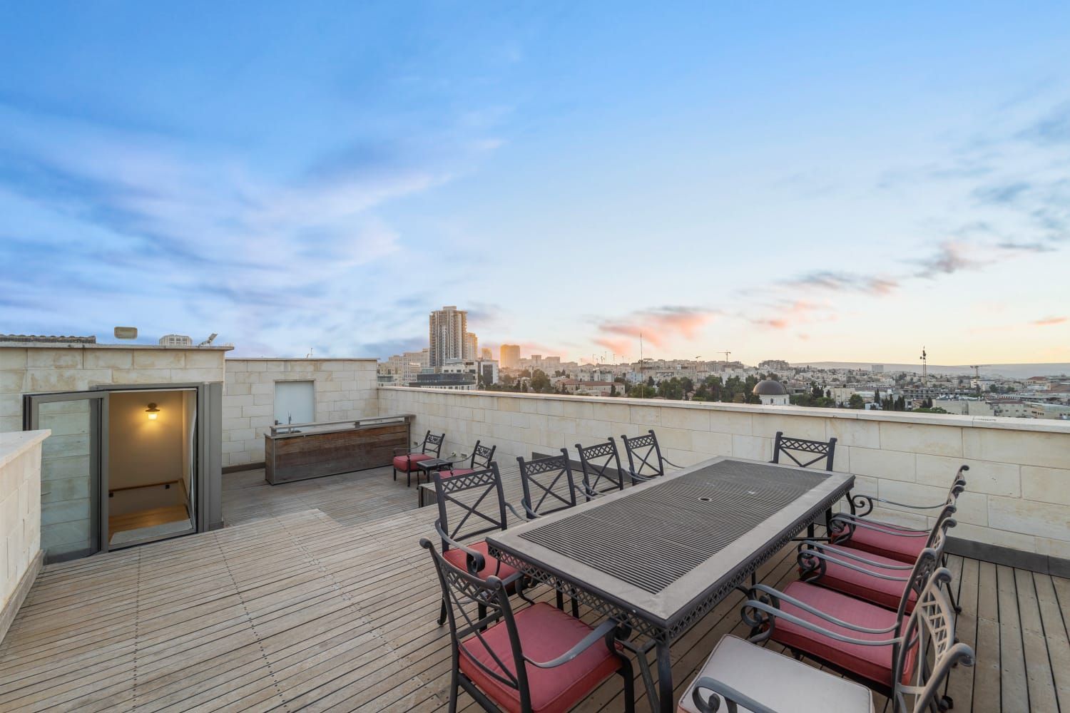 A rooftop deck with a table and chairs and a view of the city. penthouse kosher airbnb jerusalem