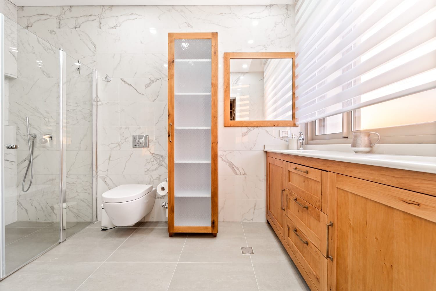 A bathroom with a toilet , sink , mirror and walk in shower.