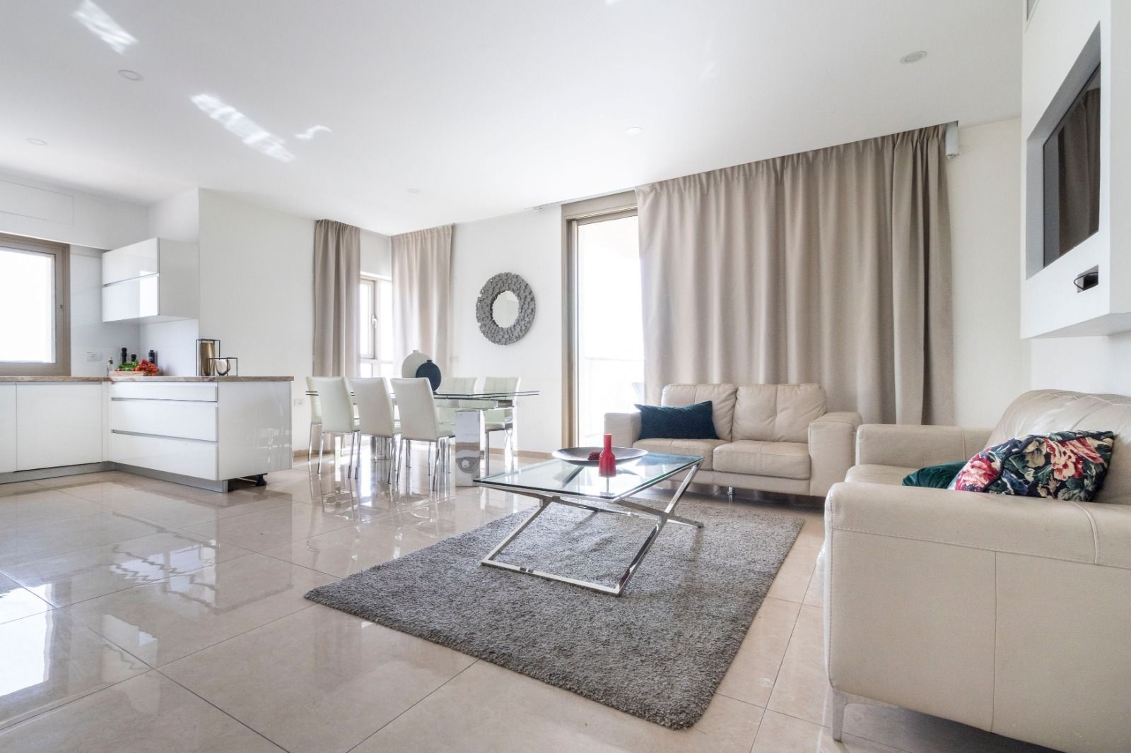 A living room with a couch , chairs , a table and a rug.