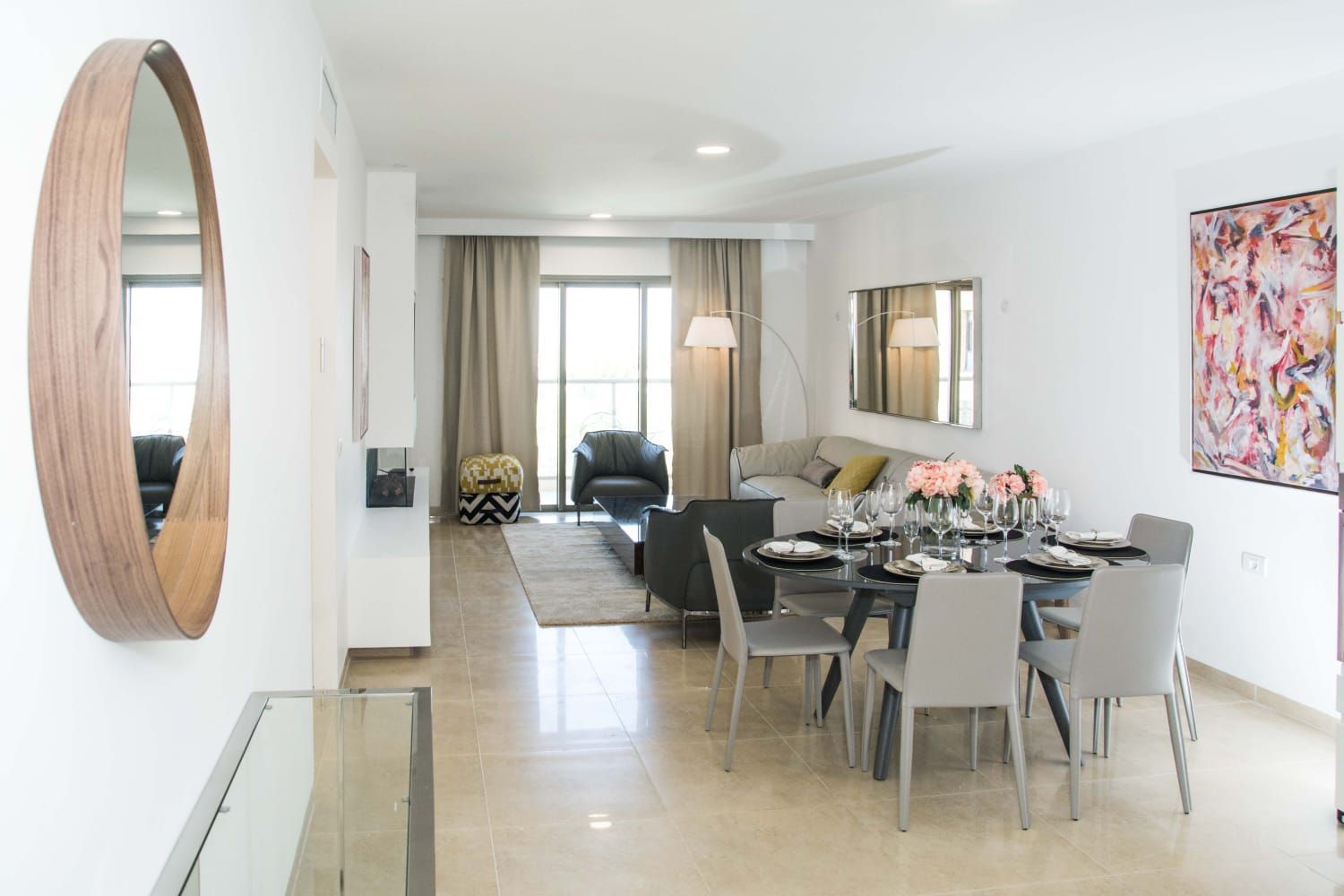 A living room with a dining table and chairs and a mirror.