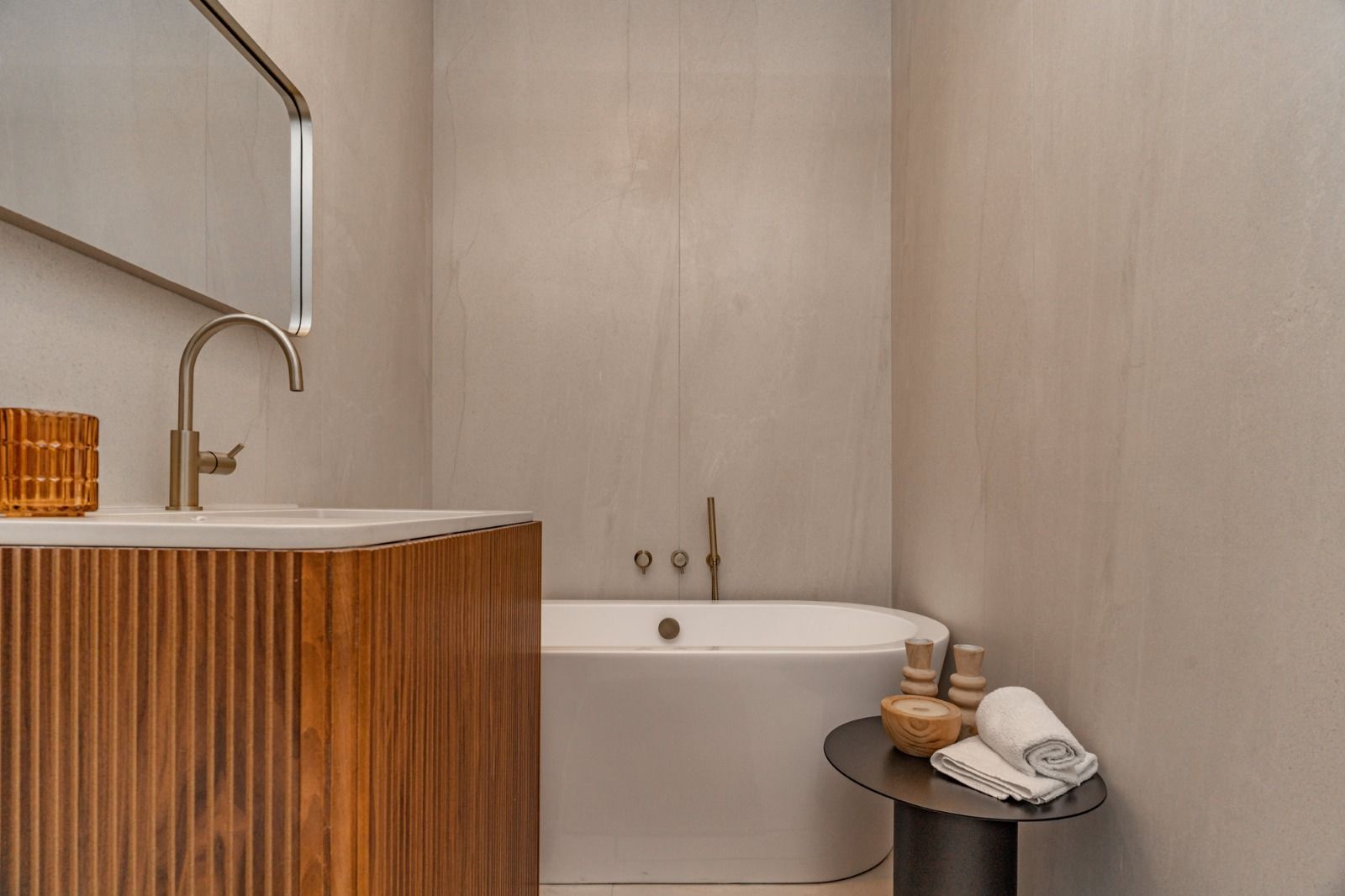 A bathroom with a bathtub , sink and mirror.