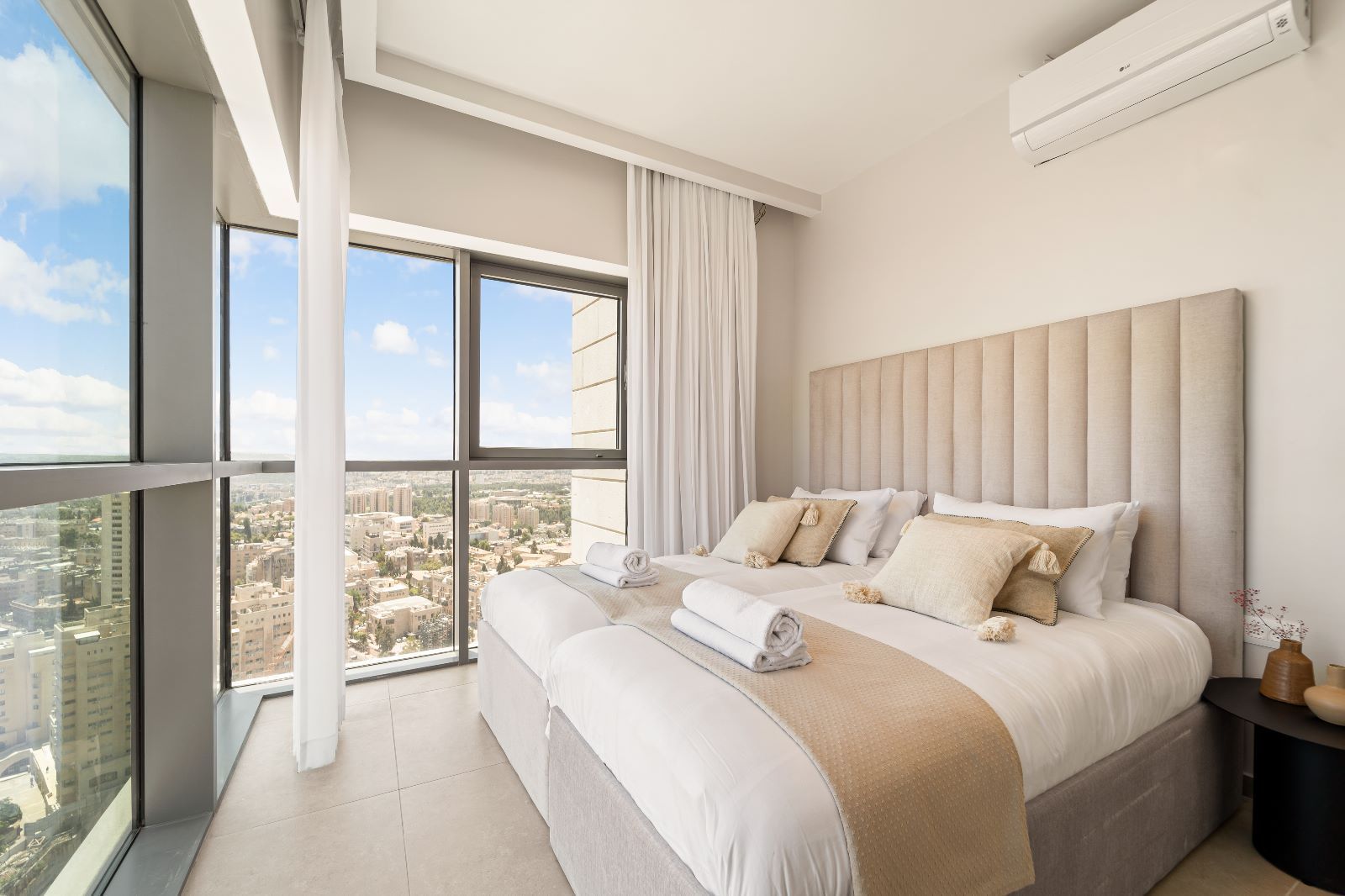 A bedroom with a kosher bed and a large window overlooking Jerusalem