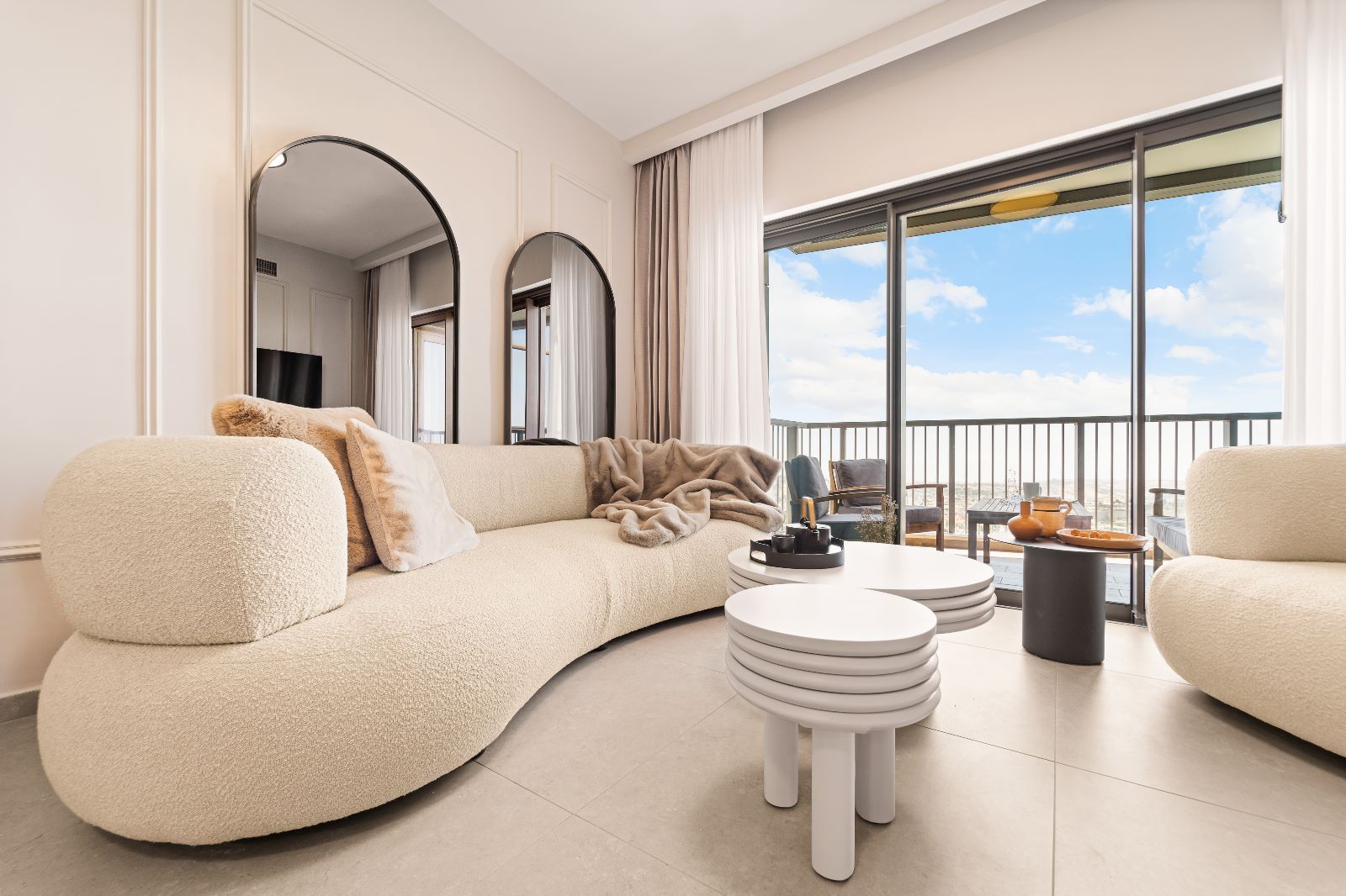 A living room with a couch , chairs , tables and a balcony.