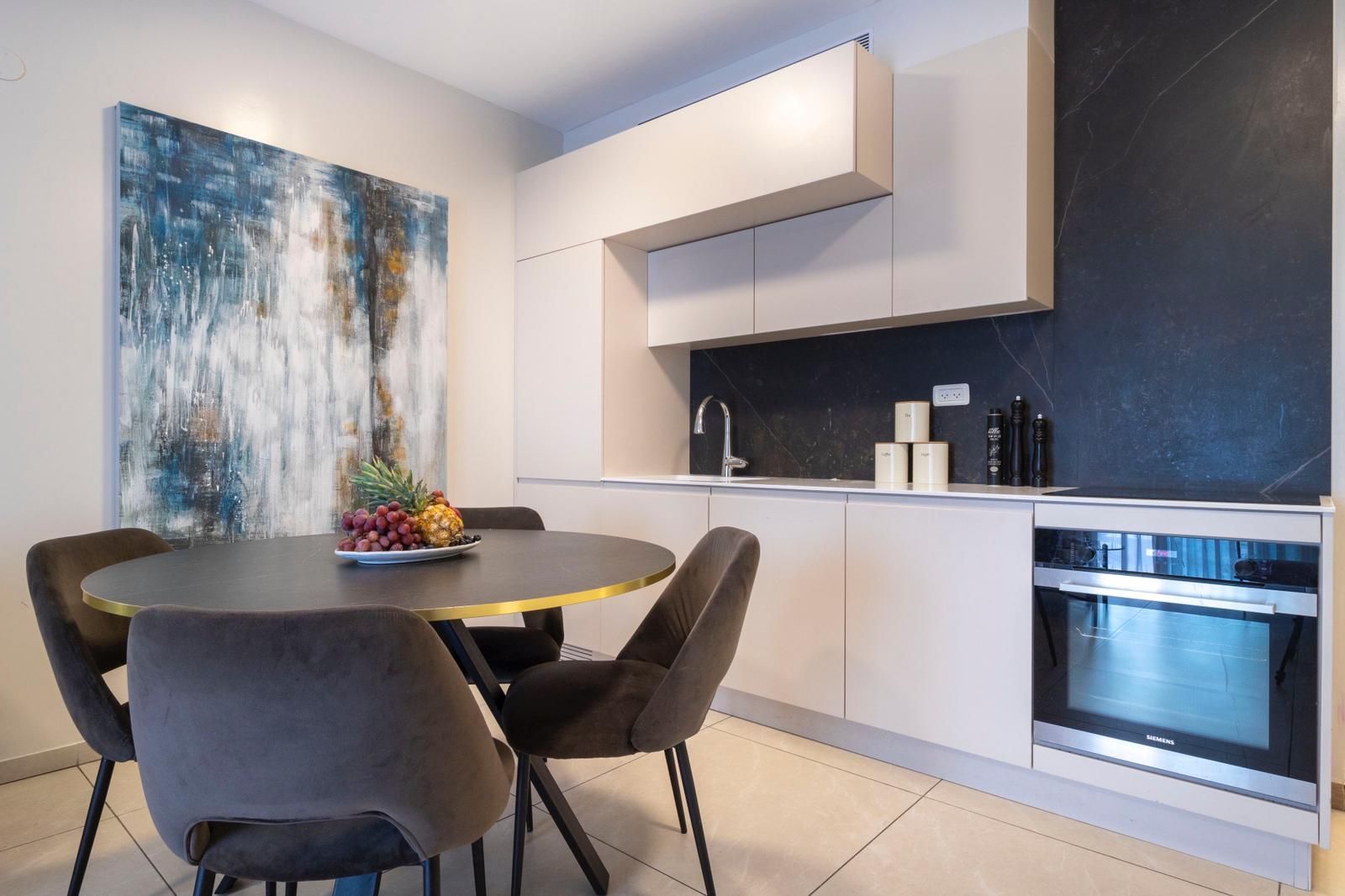 A kitchen with a table and chairs and a painting on the wall.