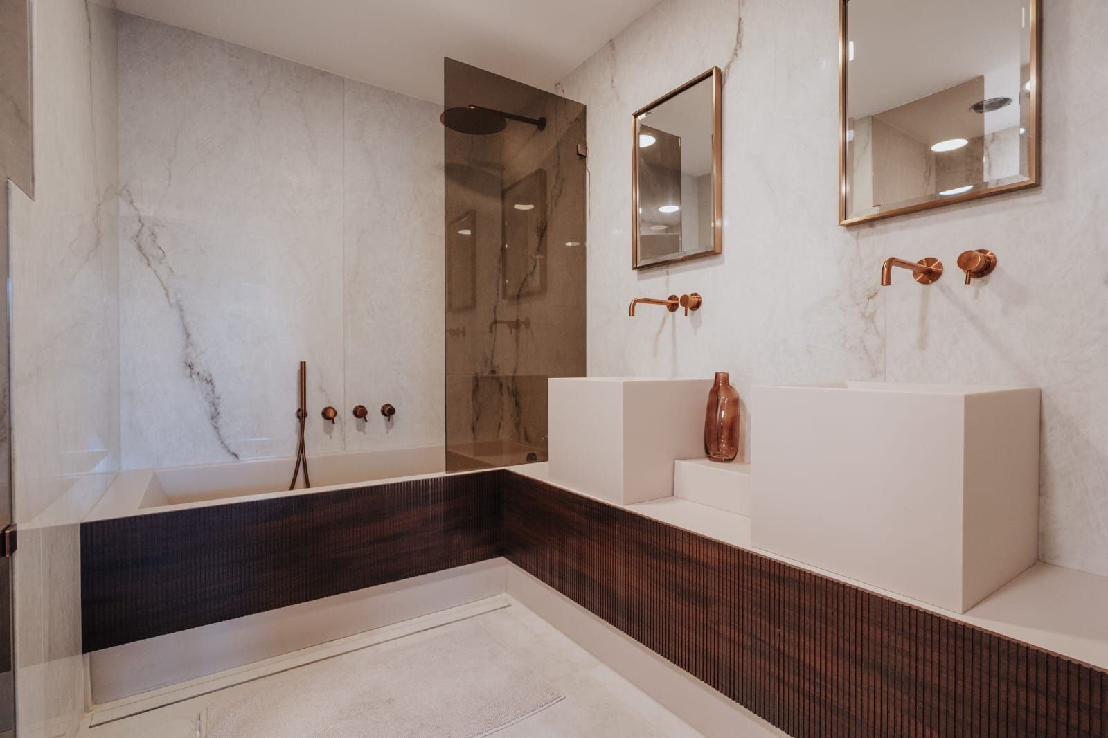 A bathroom with two sinks , a tub , and a mirror.