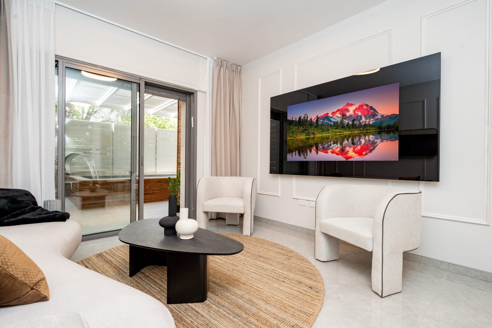 A living room with a couch , chairs , coffee table and television.