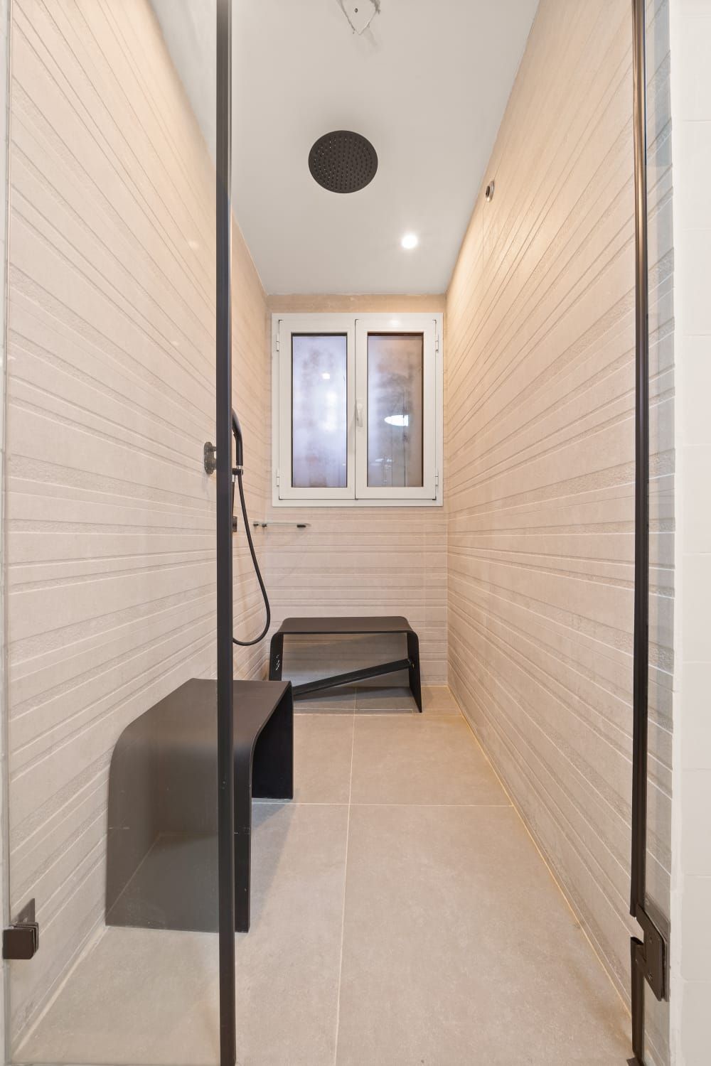 A bathroom with a shower , a bench , and a window. Sauna Shower