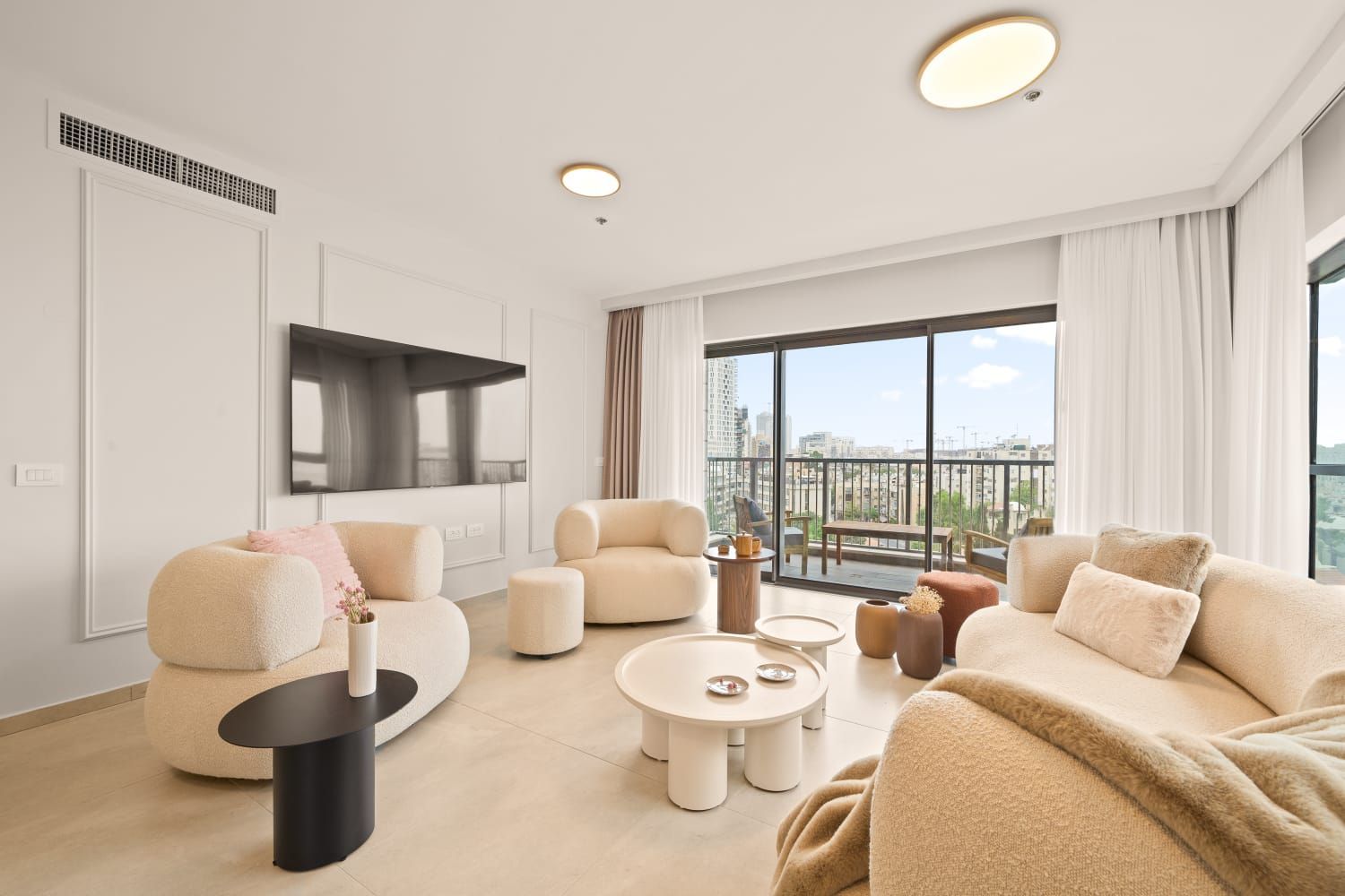 A living room with a couch , chairs , tables and a flat screen tv.