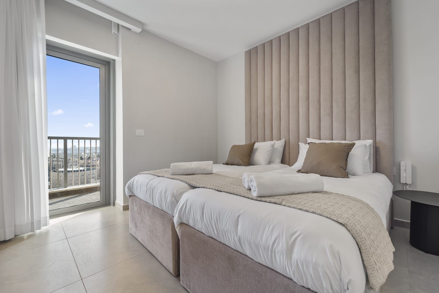 A hotel room with two beds and a balcony.