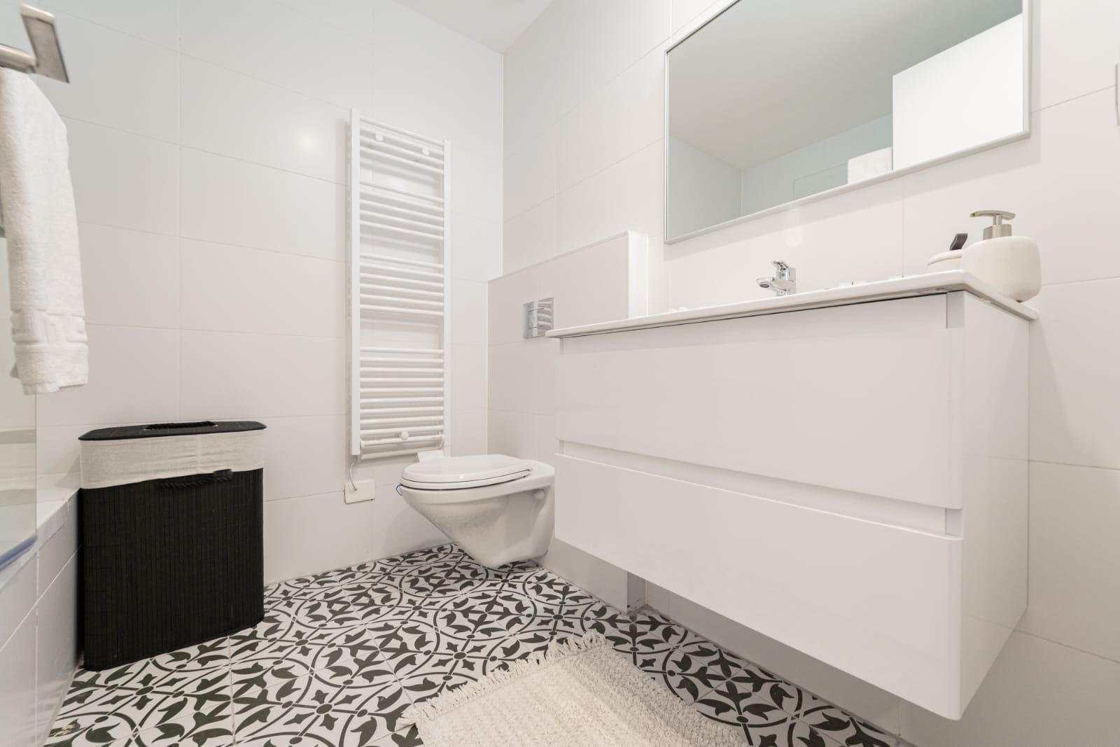 A bathroom with a toilet , sink , mirror and towel rack.