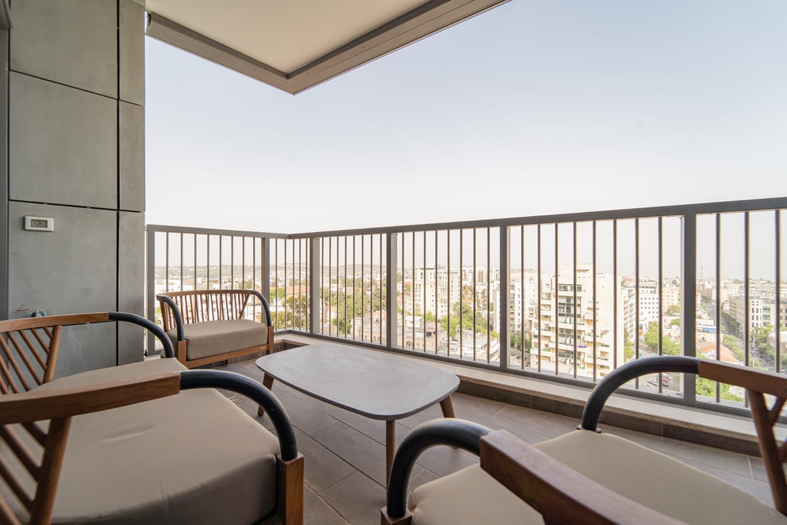 A balcony with two chairs and a table with a view of the city.