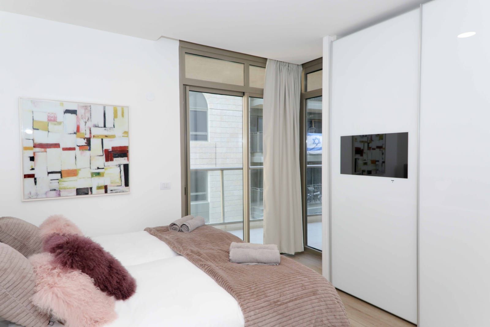 A bedroom with a bed and a television on the wall.