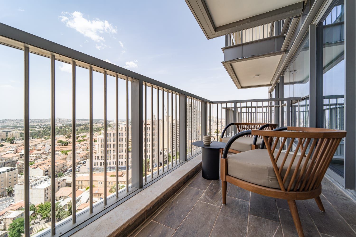 A balcony with two chairs and a table with a view of the city.