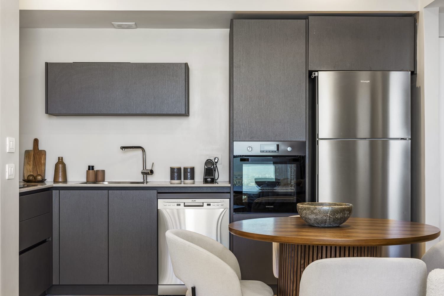 A kitchen with a stainless steel refrigerator and a wooden table.