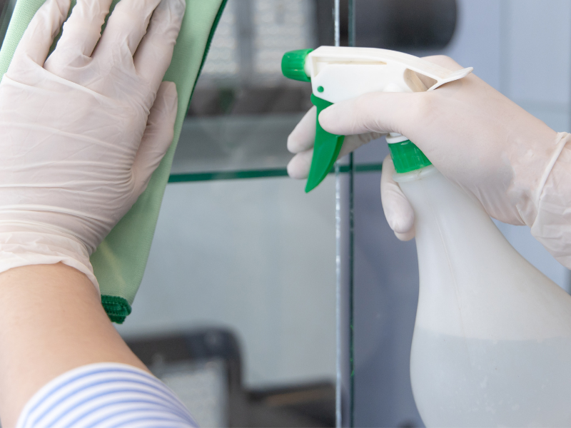 A person is cleaning a mirror with a cloth and spray bottle