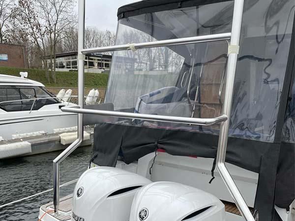Ein Boot mit klarer Windschutzscheibe liegt in einem Yachthafen vor Anker.