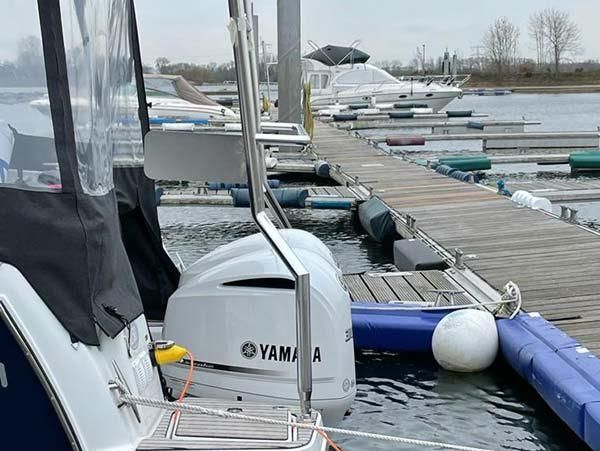 In einem Yachthafen neben einem Dock liegt ein Boot vor Anker.