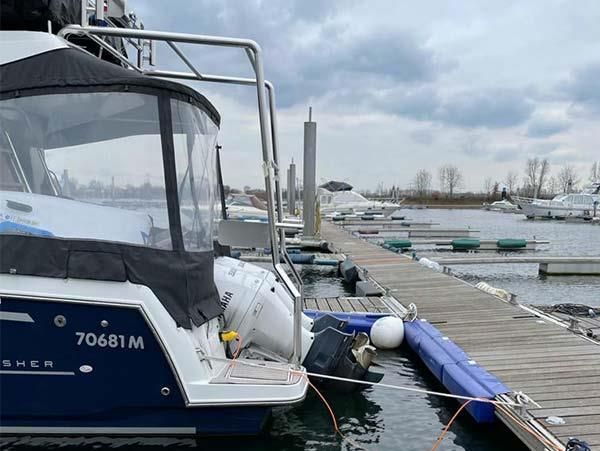 In einem Yachthafen liegt ein blau-weißes Boot vor Anker.