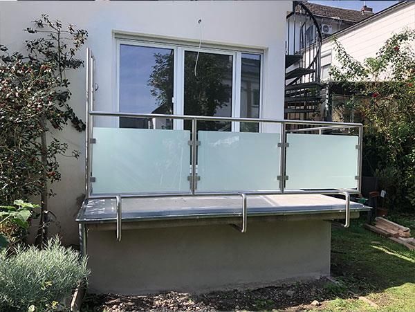 Ein Balkon mit Edelstahlgeländer und einer Wendeltreppe im Hintergrund