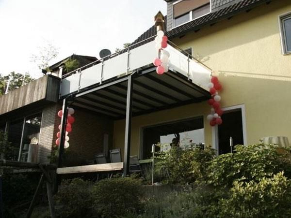Ein gelbes Haus mit einem Balkon, der mit roten und weißen Luftballons dekoriert ist