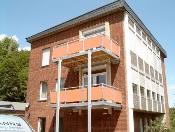 Ein Backsteingebäude mit orangefarbenen Balkonen und einem Lieferwagen mit der Aufschrift „Anns“